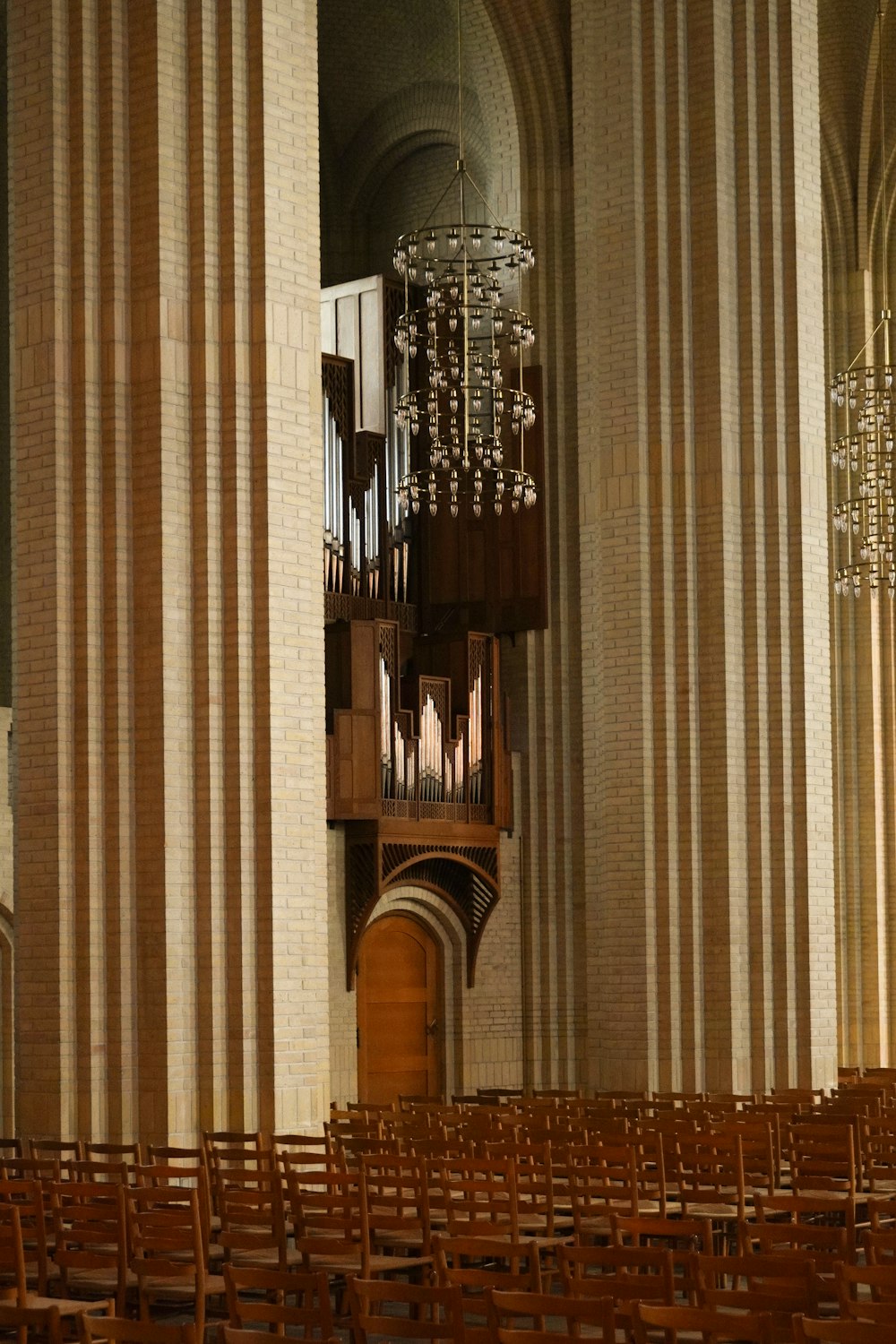 a church filled with wooden chairs and a chandelier