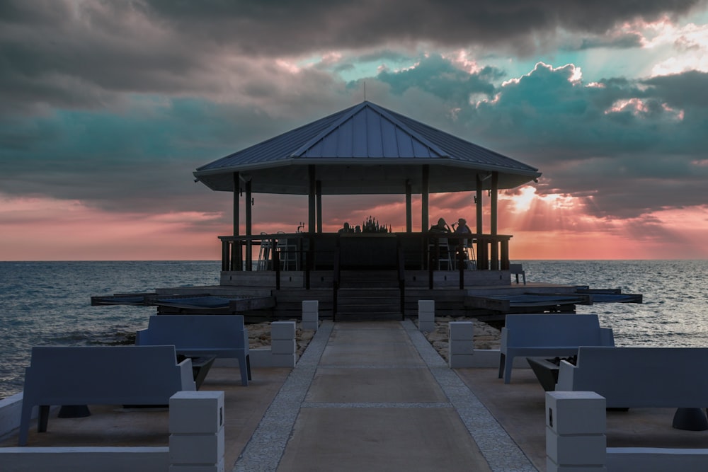 a gazebo sitting on the end of a pier next to the ocean