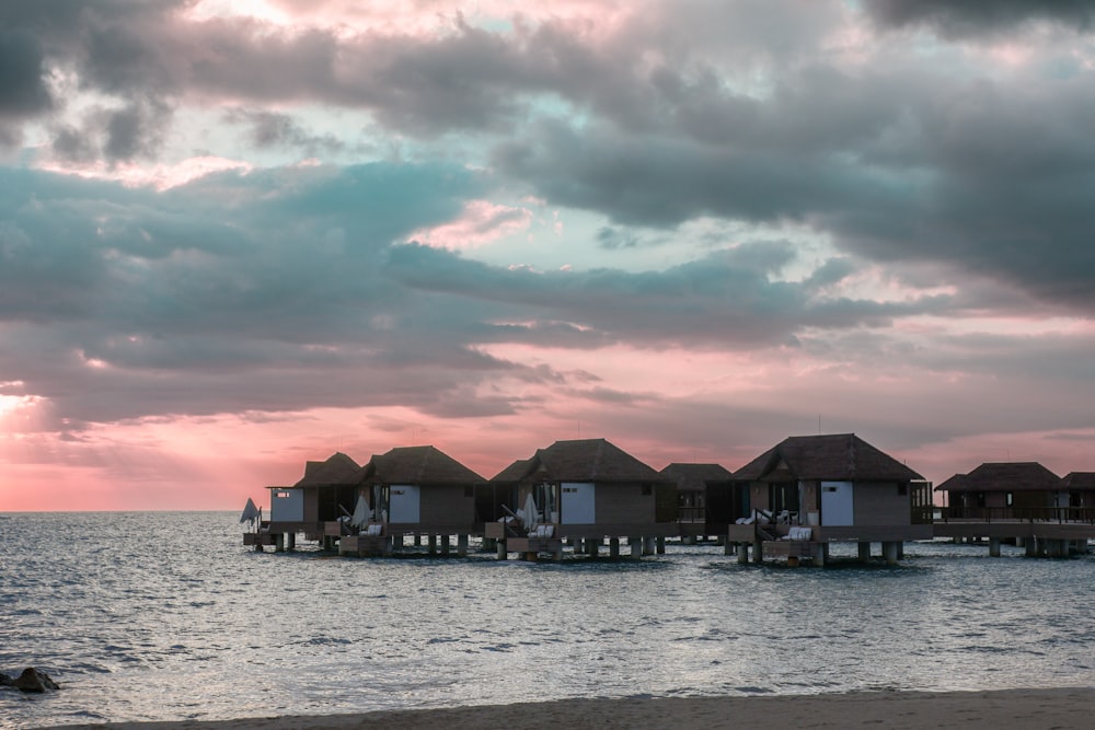 a row of houses sitting on top of a beach next to the ocean