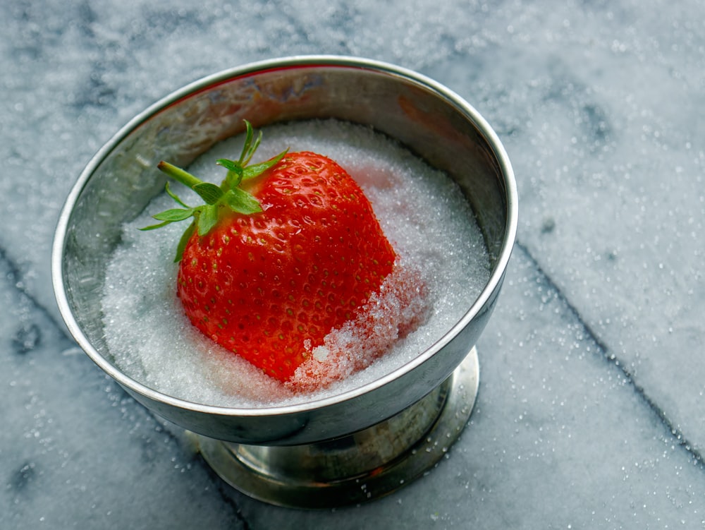 a strawberry in a bowl of ice on a table