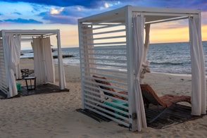 a couple of white cabanas sitting on top of a sandy beach