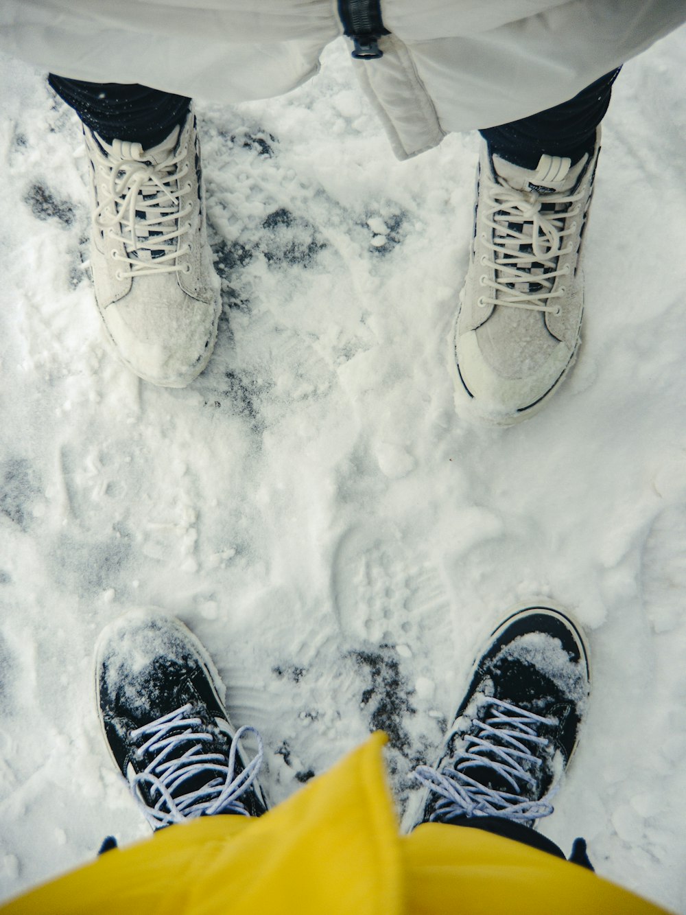 two people standing in the snow with their feet up