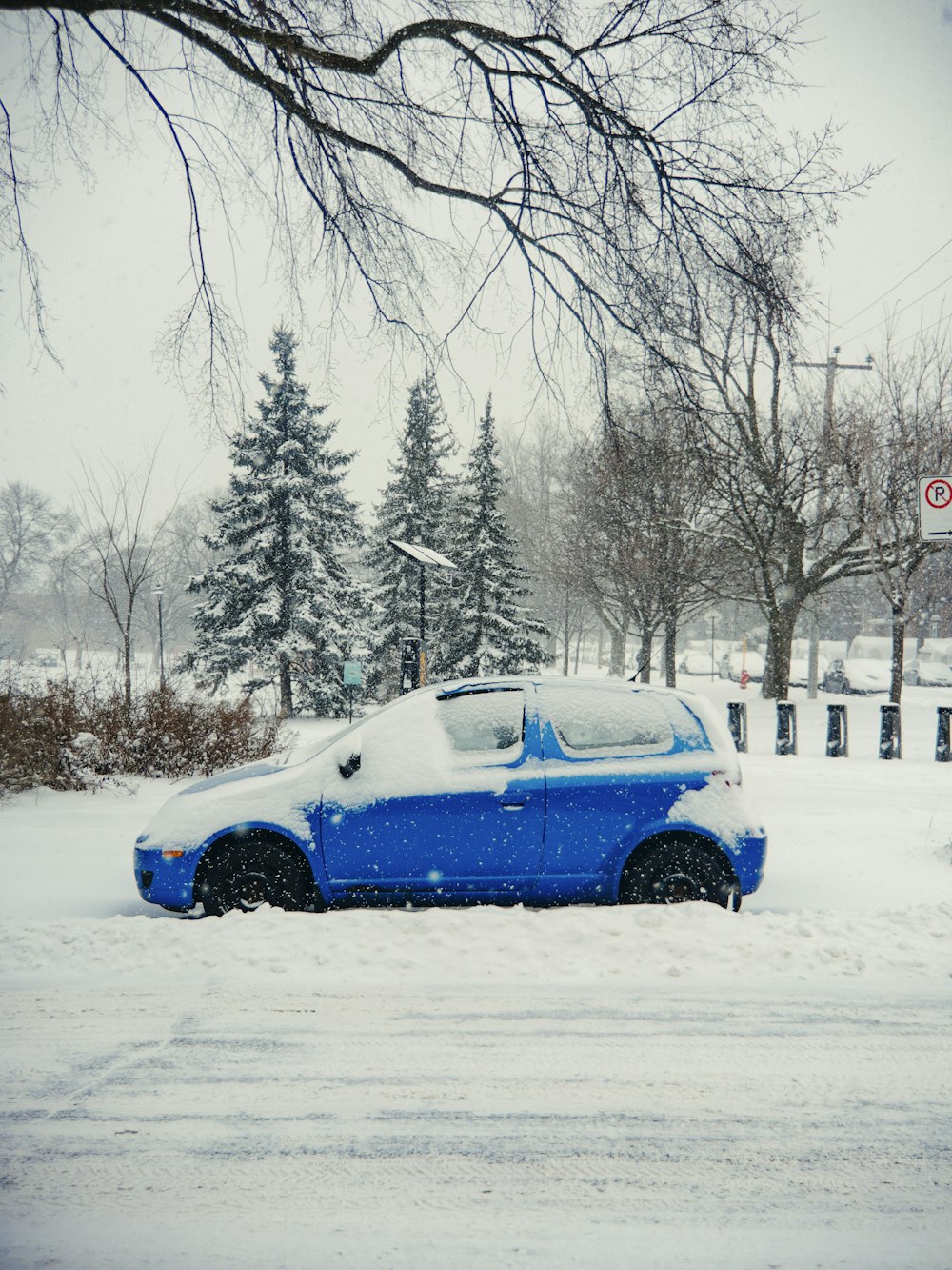 Une voiture bleue est garée dans la neige