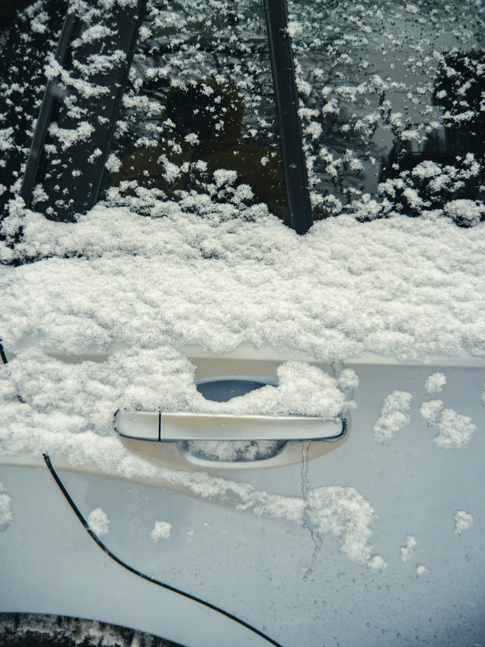 un'auto coperta di neve con la maniglia di una portiera