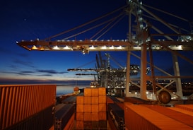 a cargo ship is docked at night with its lights on