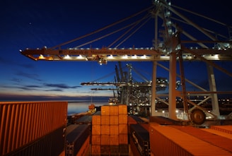 a cargo ship is docked at night with its lights on