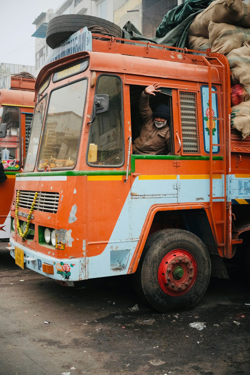 an orange and blue truck parked next to a pile of bags