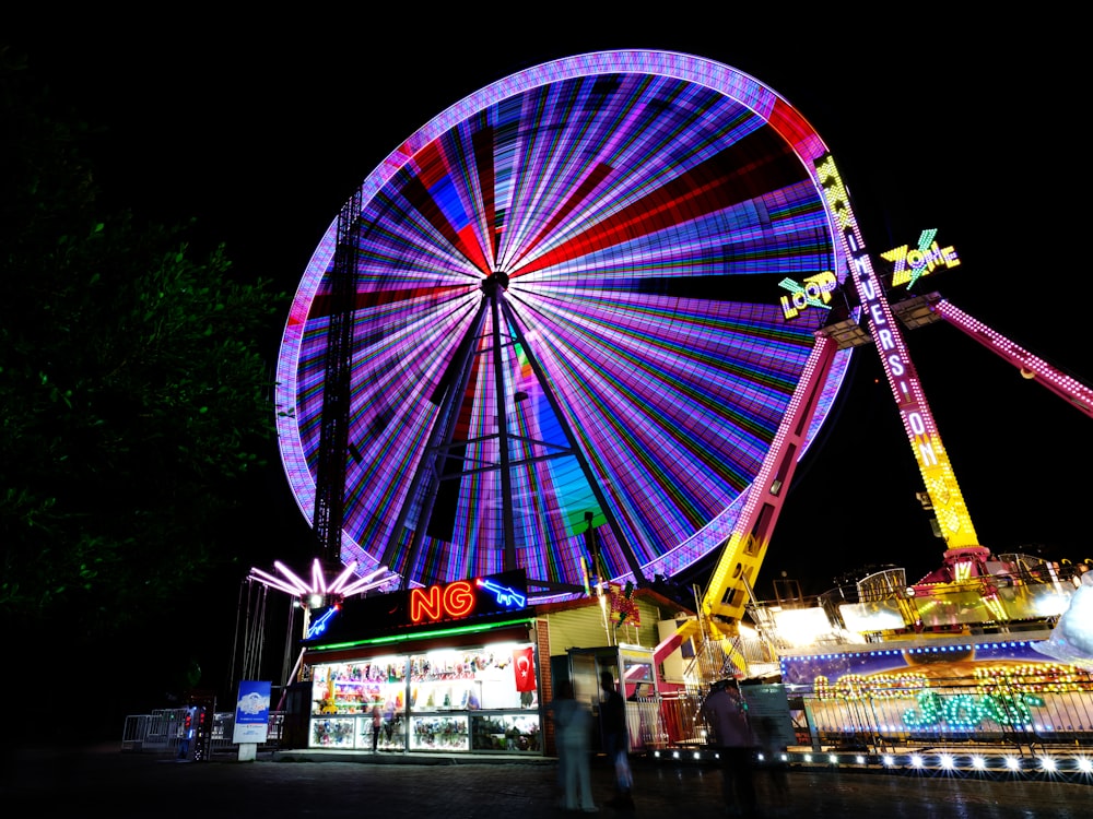 a ferris wheel lit up at night at a carnival