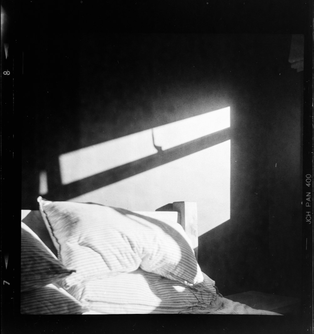 a black and white photo of a bed with a pillow