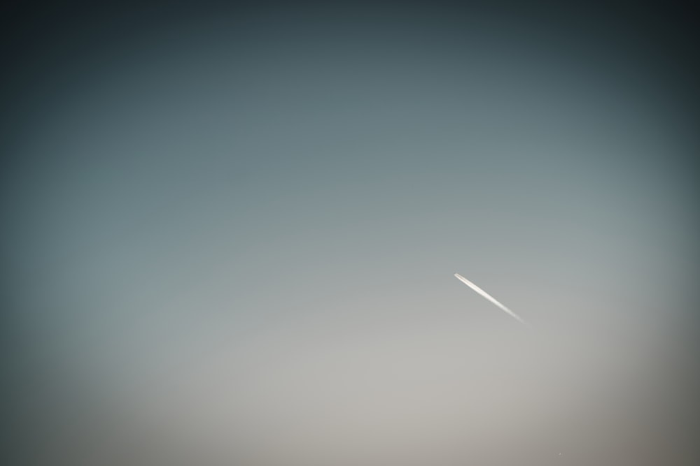 an airplane flying in the sky with a contrail in the background