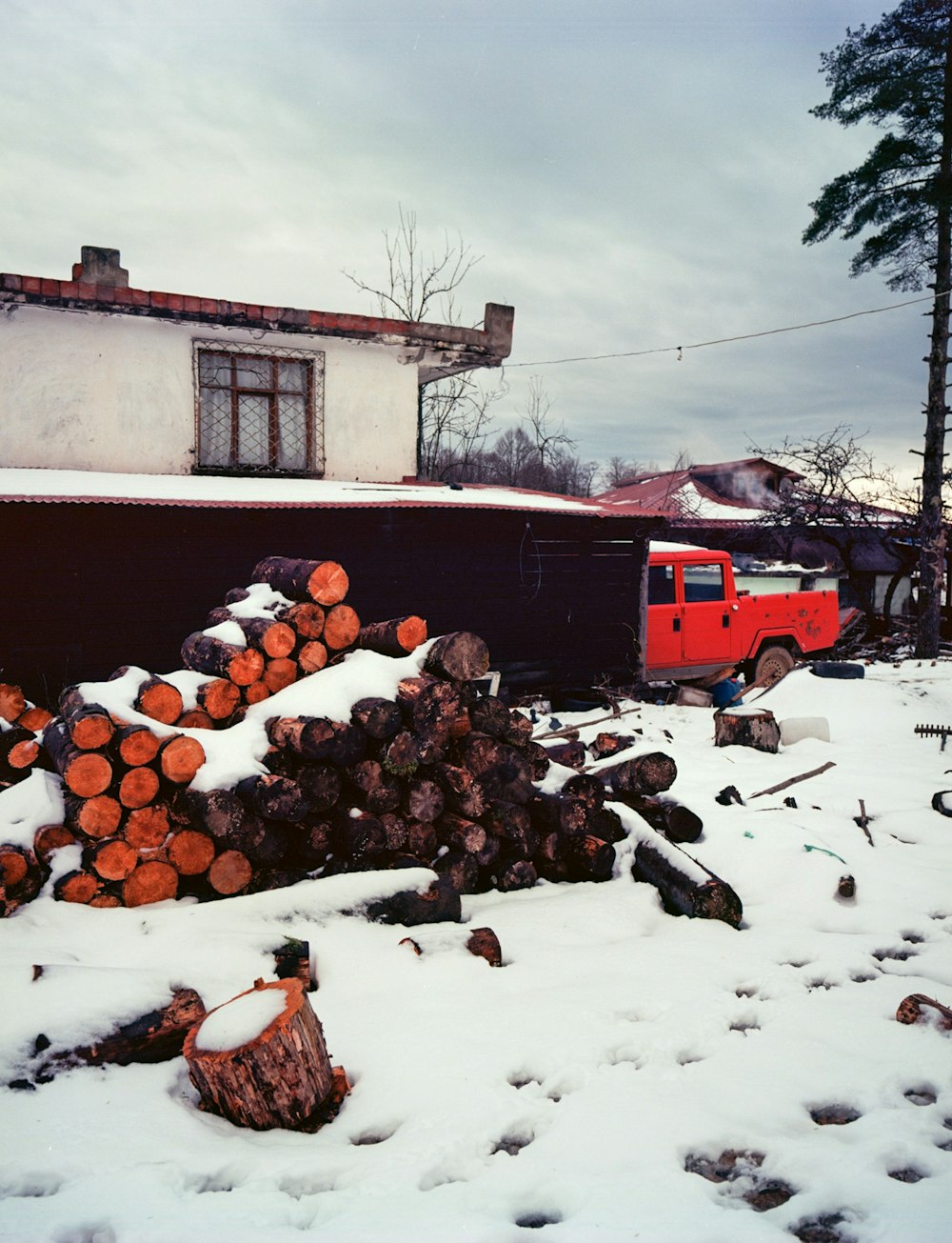 a red truck parked next to a pile of logs