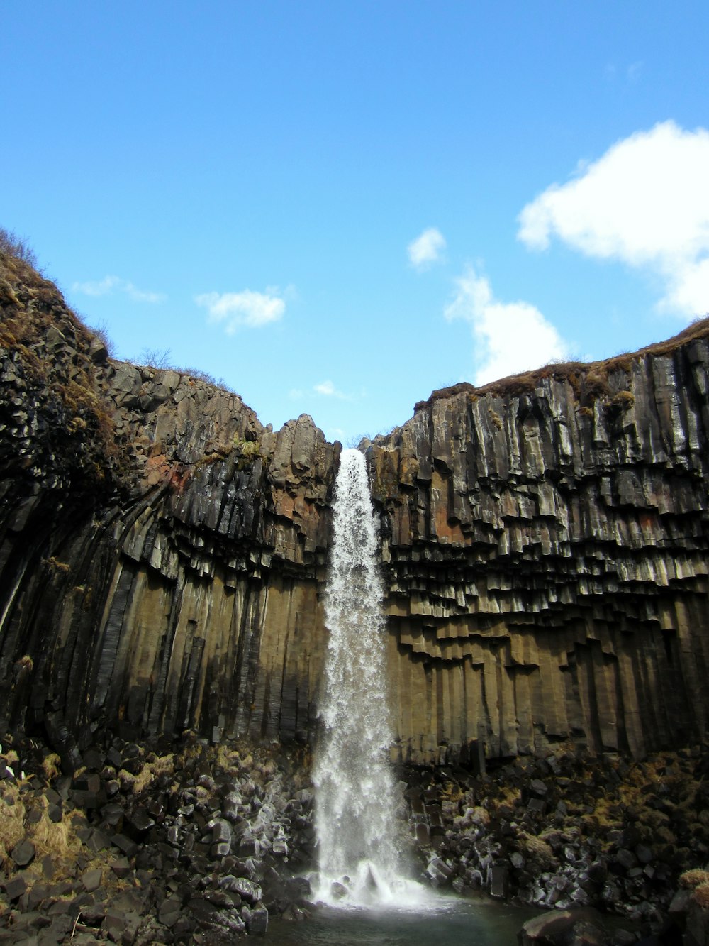 a waterfall is seen from the bottom of a cliff