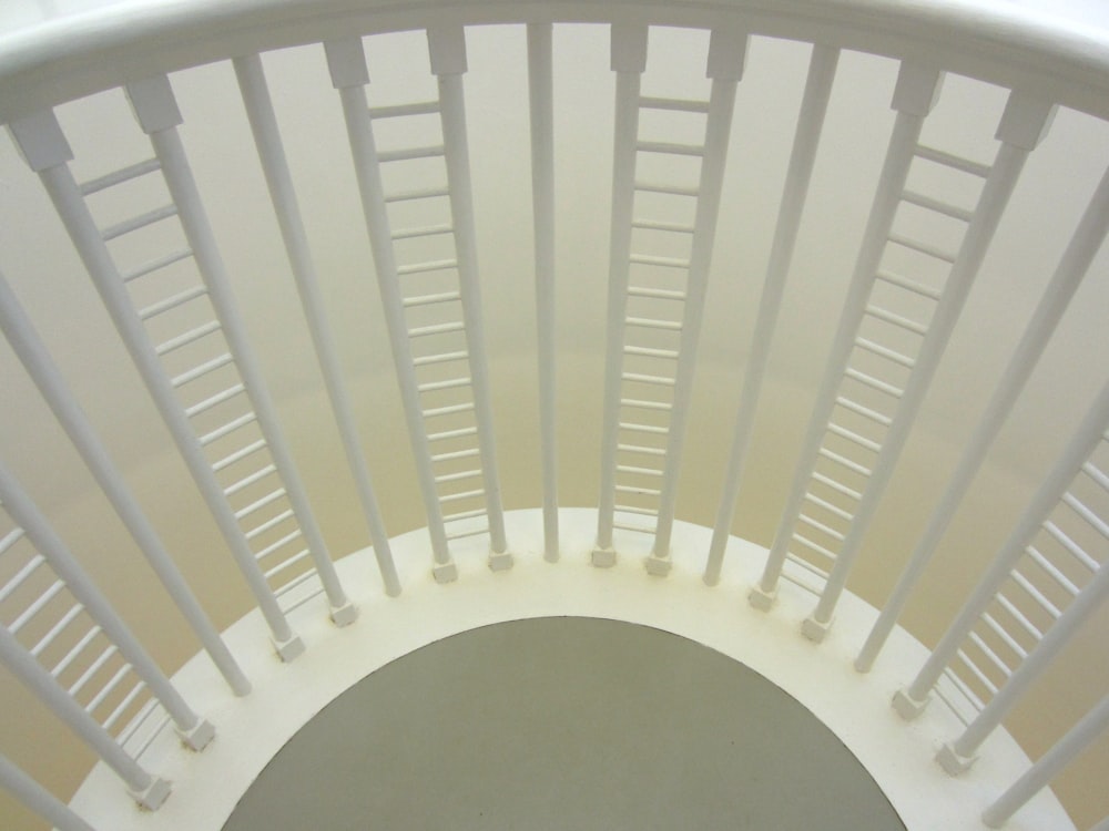 a white spiral staircase with white railings leading up to the top