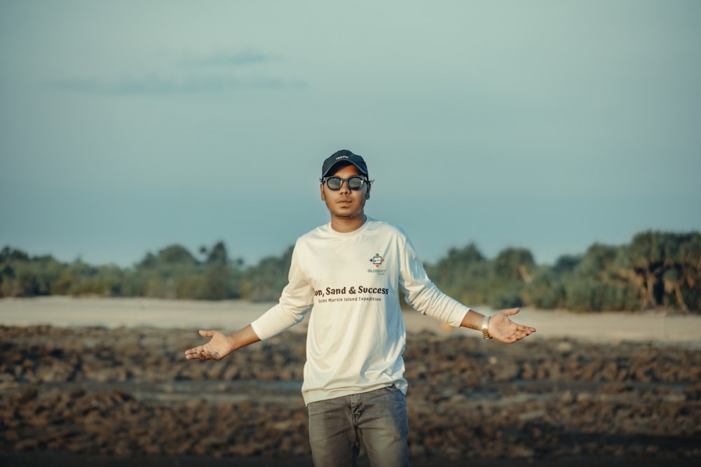 a man wearing a hat and sunglasses standing in a field