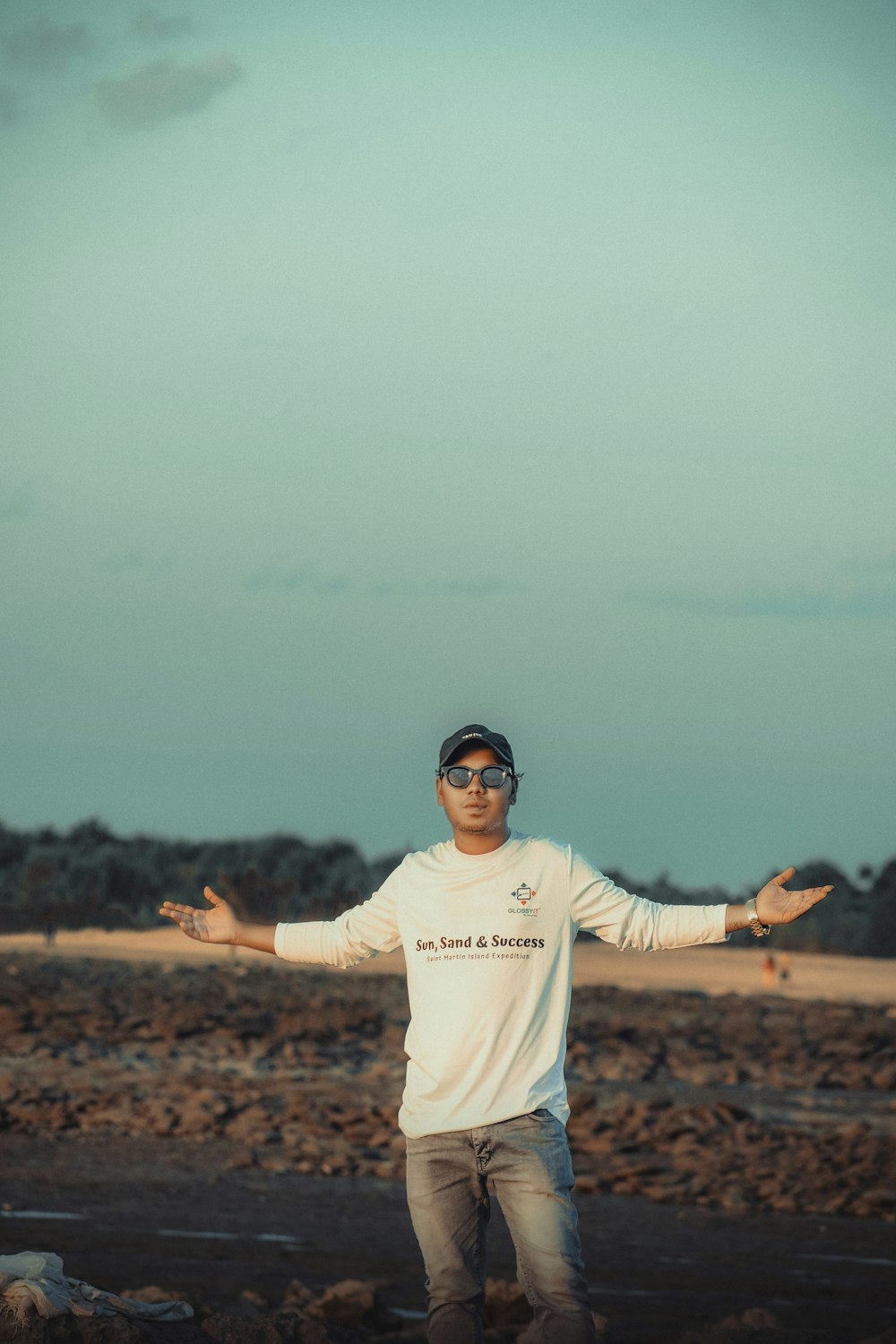 a man standing on a beach with his arms outstretched