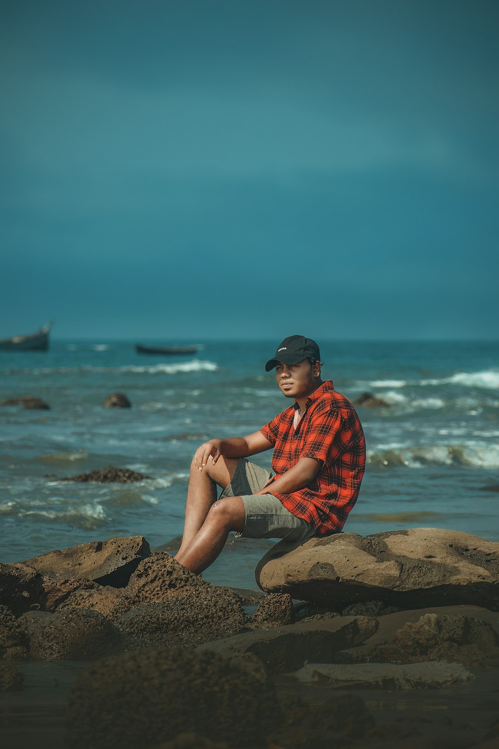 a man sitting on a rock near the ocean