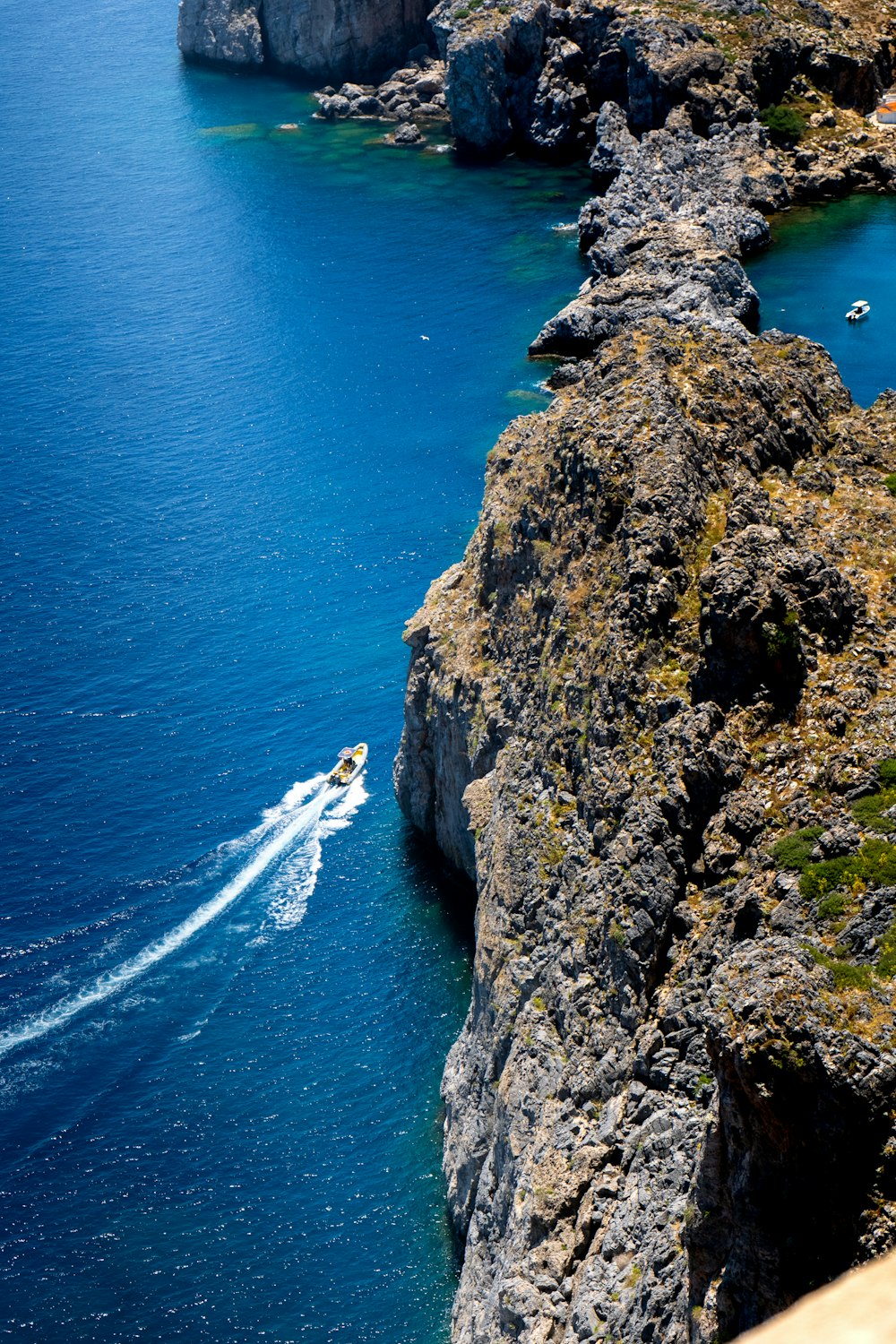 a boat traveling through a body of water next to a rocky cliff
