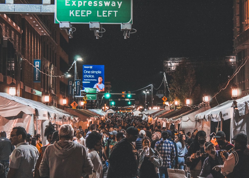 a crowd of people walking down a street at night