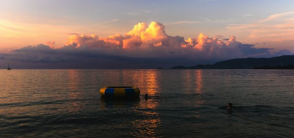 A couple of people swimming in the ocean under a cloudy sky — Koh Samui, Thailand