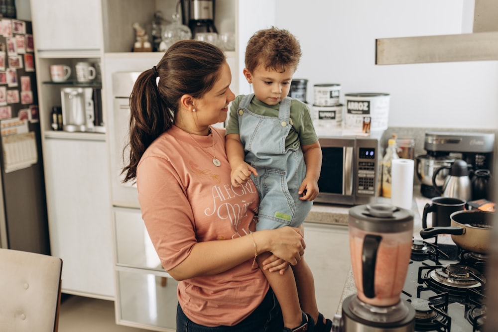 a woman holding a child in a kitchen