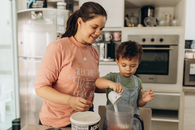 a woman standing next to a child in a kitchen