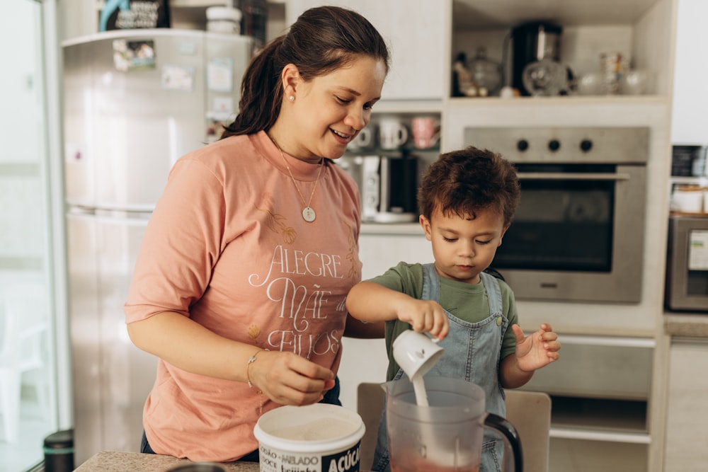 a woman standing next to a child in a kitchen