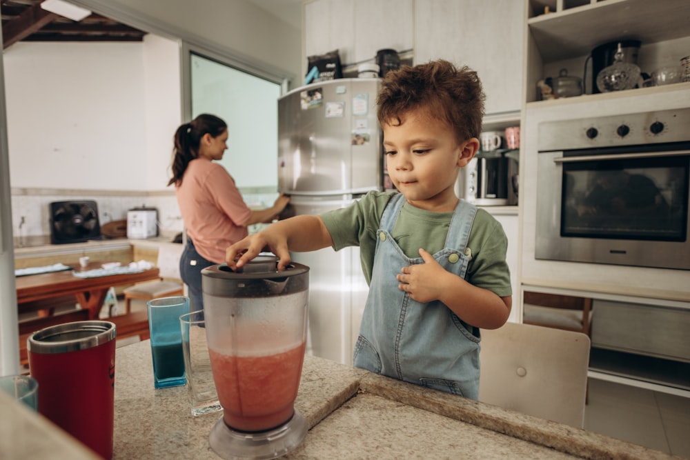 a young boy is making a smoothie in a blender