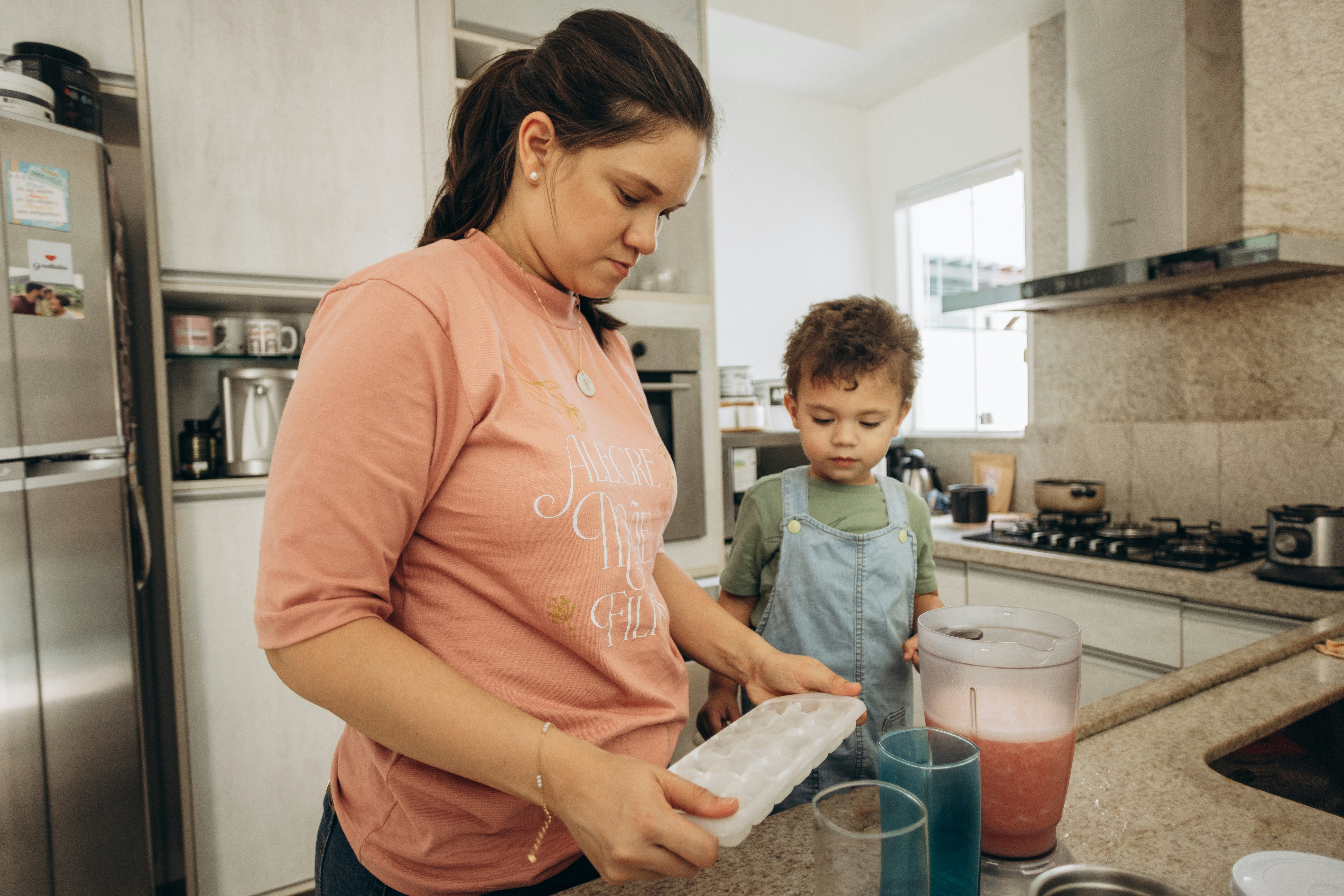 A family working together in a bright, organized kitchen, using the EasyHome app on a tablet to check their daily chores and meal plan.
