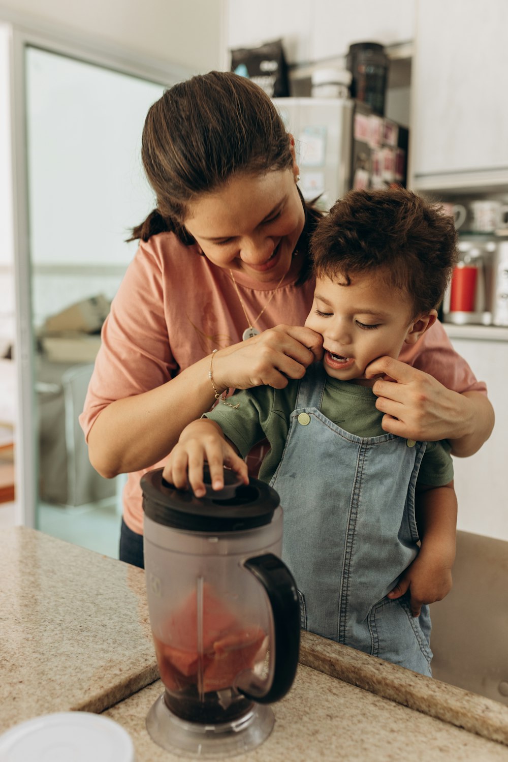 a woman and a child are making something in a blender