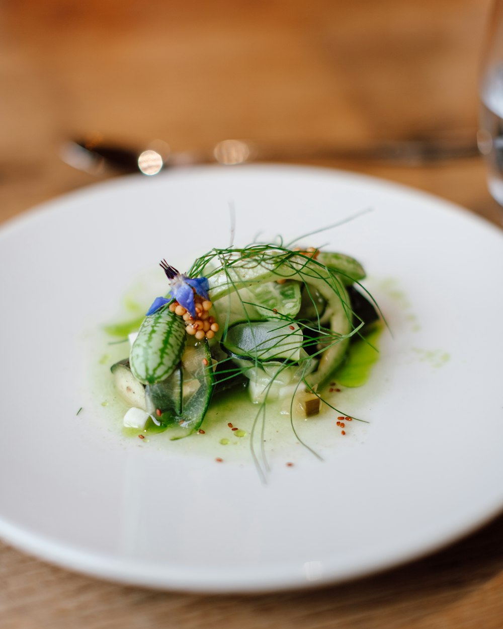 une assiette blanche garnie de concombres recouverts de sauce verte