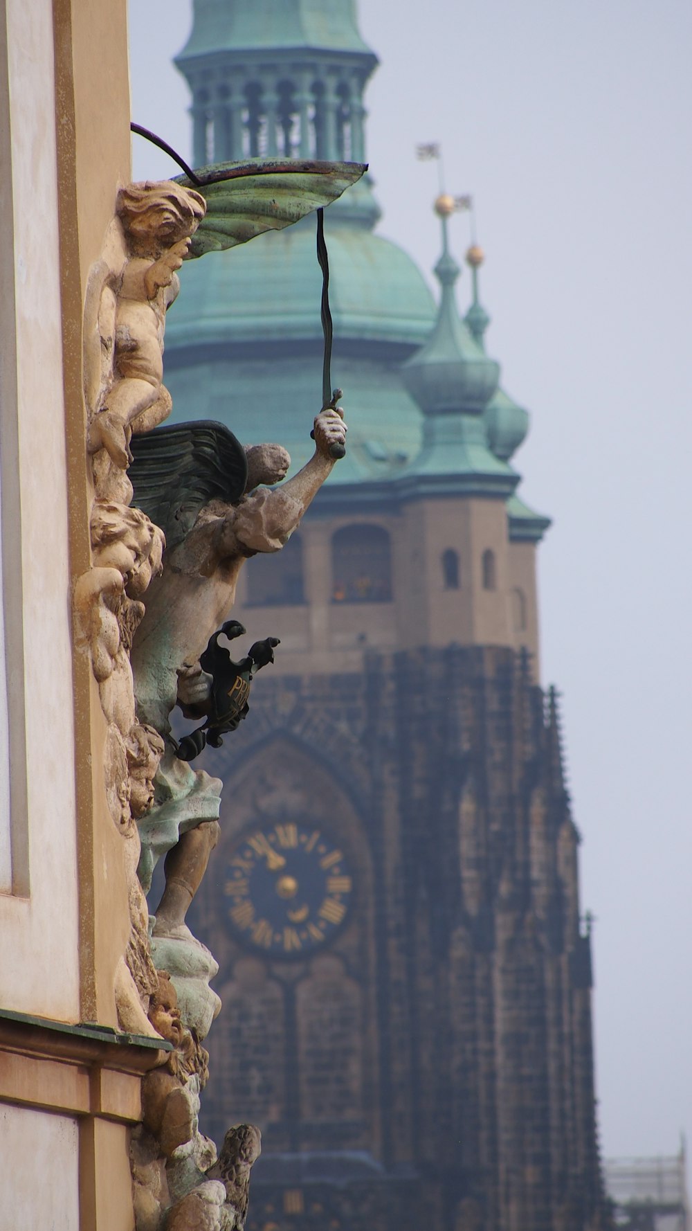 a statue on the side of a building with a clock tower in the background