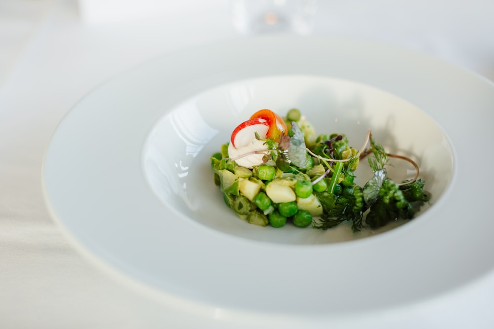 une assiette blanche garnie d’une salade recouverte de légumes