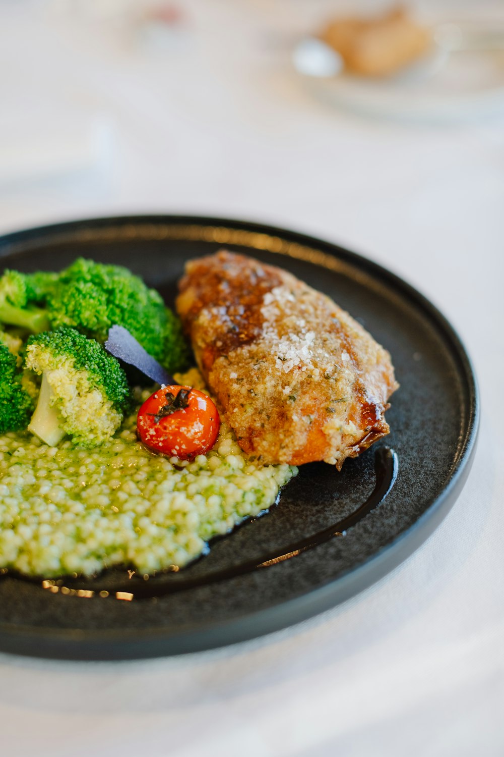 une assiette noire garnie de viande et de légumes