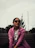 a woman in a pink coat and sunglasses sitting on a bench