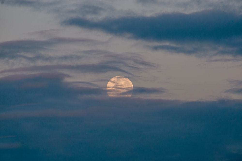 a full moon is seen through the clouds