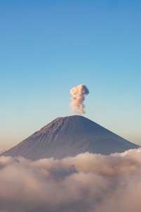 a volcano spewing smoke in the sky above the clouds
