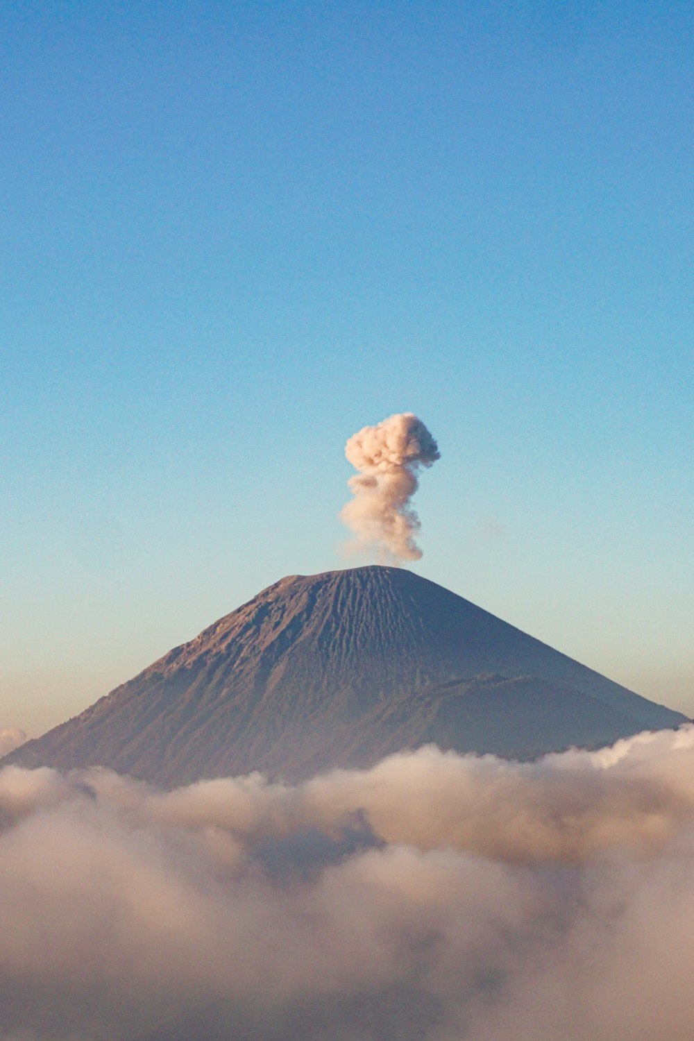 un volcan crachant de la fumée dans le ciel au-dessus des nuages