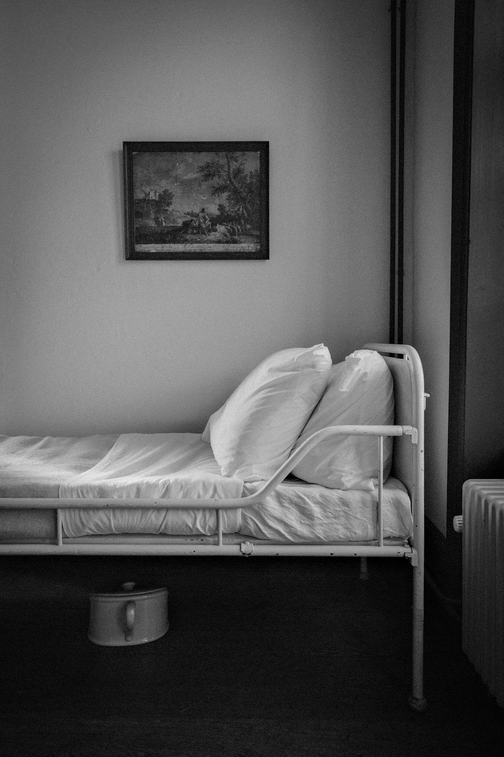 a single bed in a small room with a painting on the wall