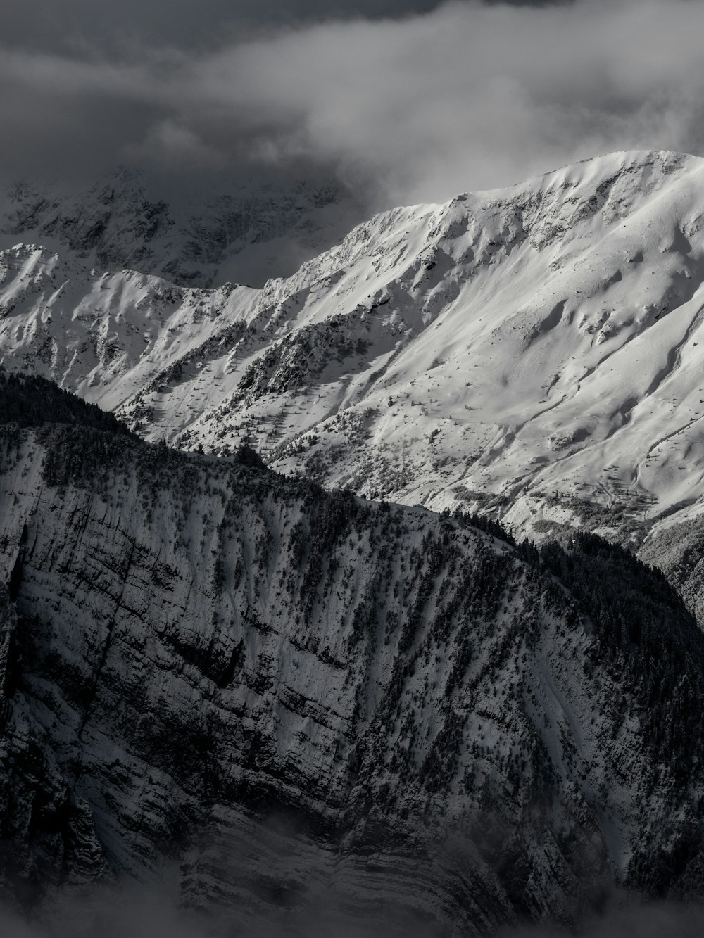 a mountain covered in snow under a cloudy sky