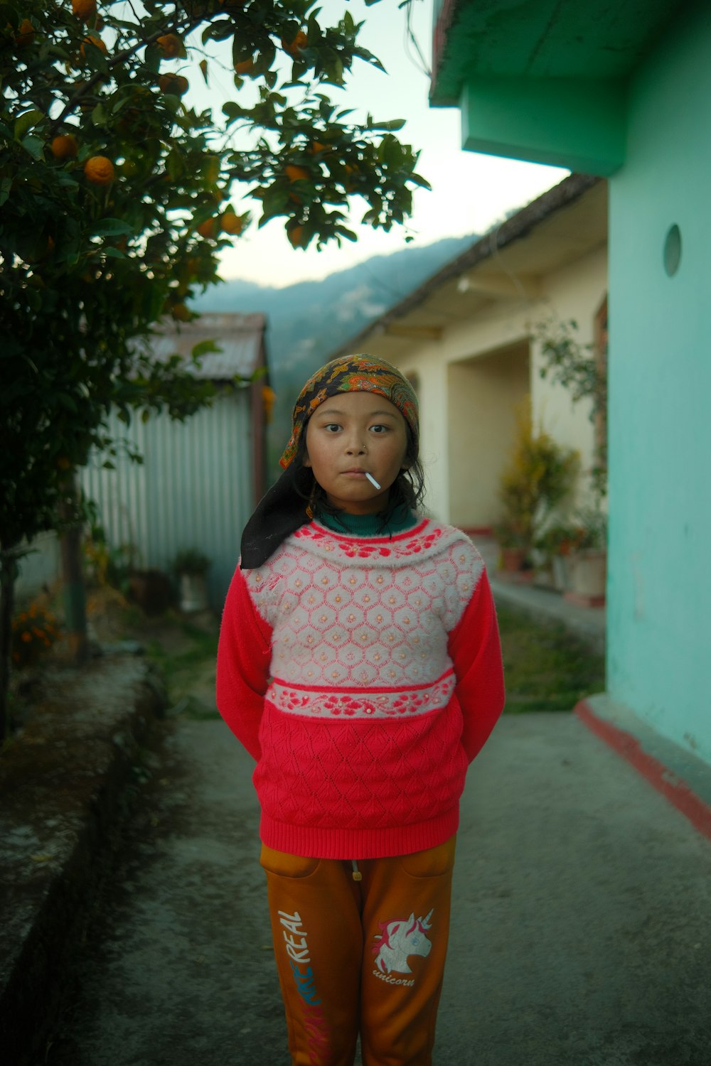 a young girl standing in front of a tree