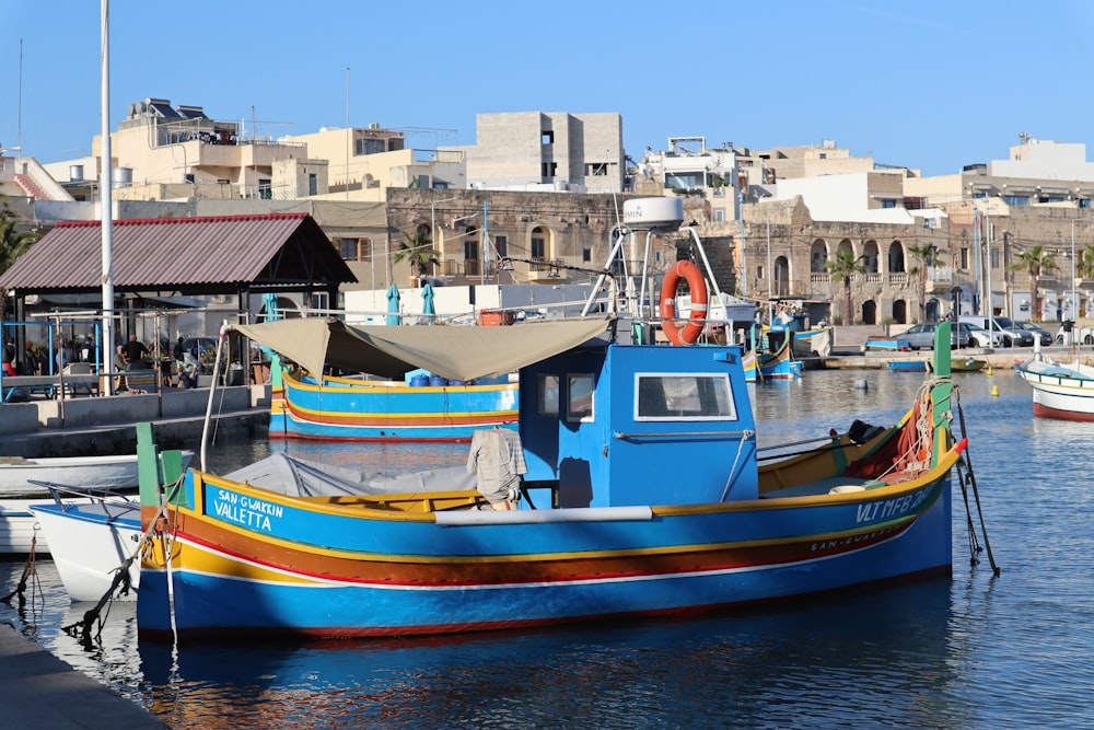 a colorful boat docked in a harbor with buildings in the background
