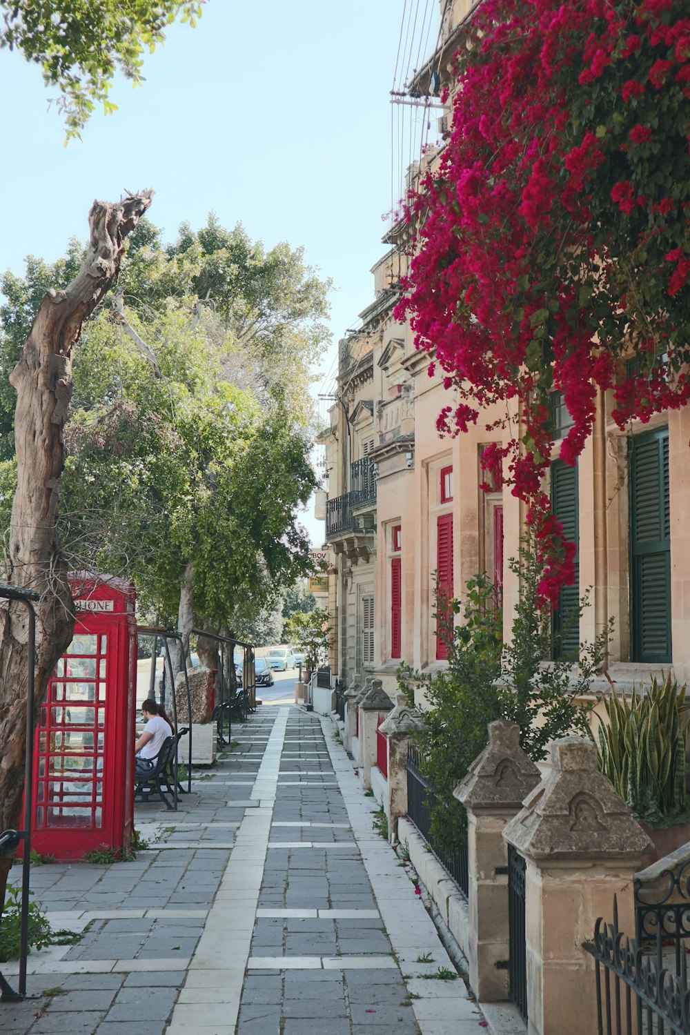 a red phone booth sitting on the side of a road