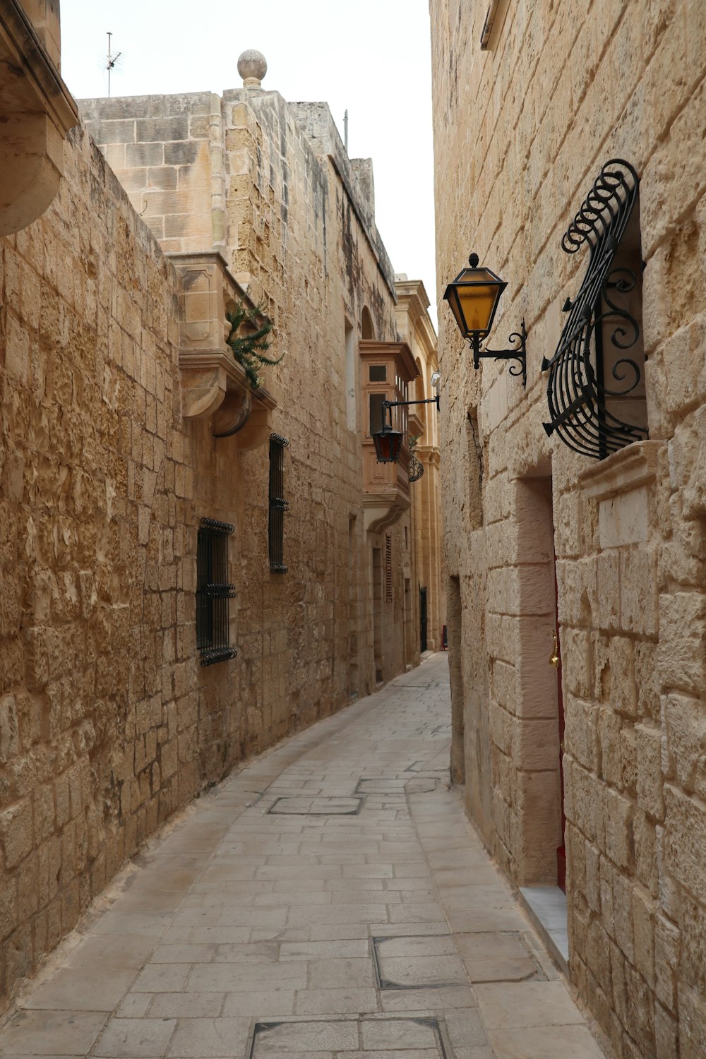 a narrow street with a lamp on the side of it