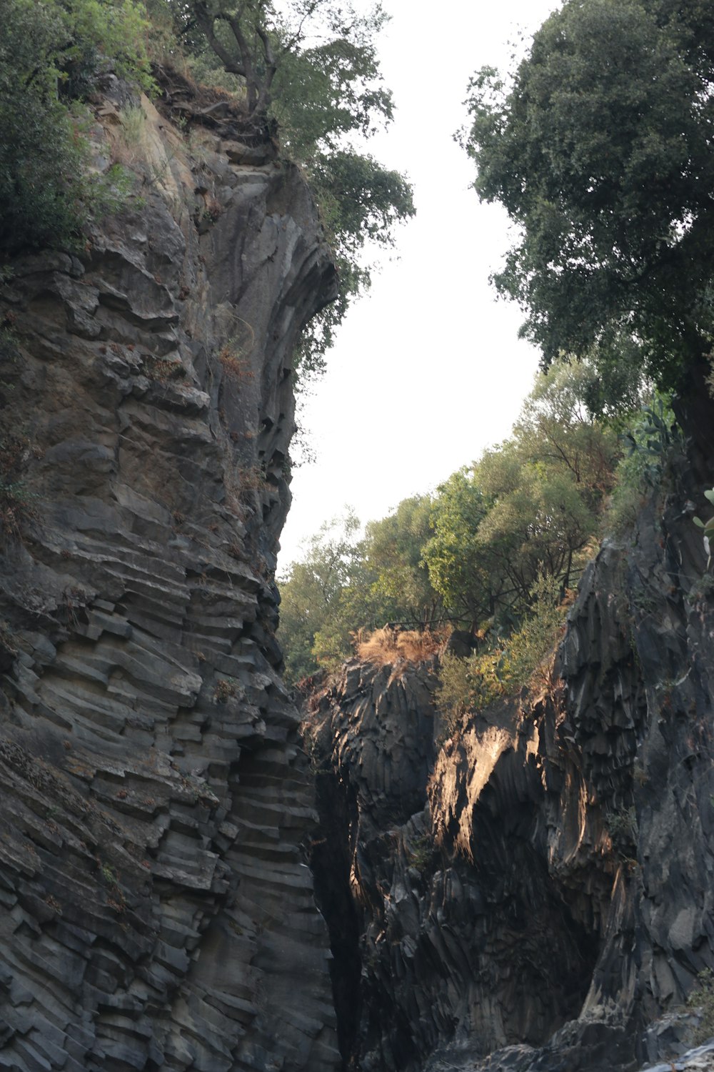 a boat traveling down a river next to a rocky cliff