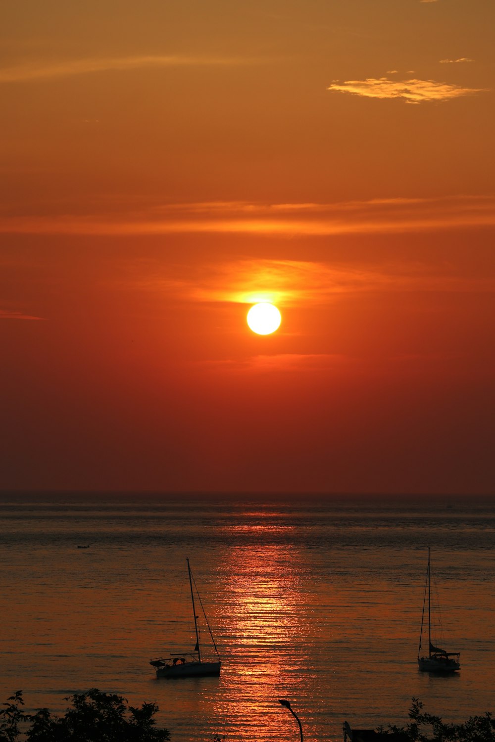 the sun is setting over the ocean with sailboats in the water