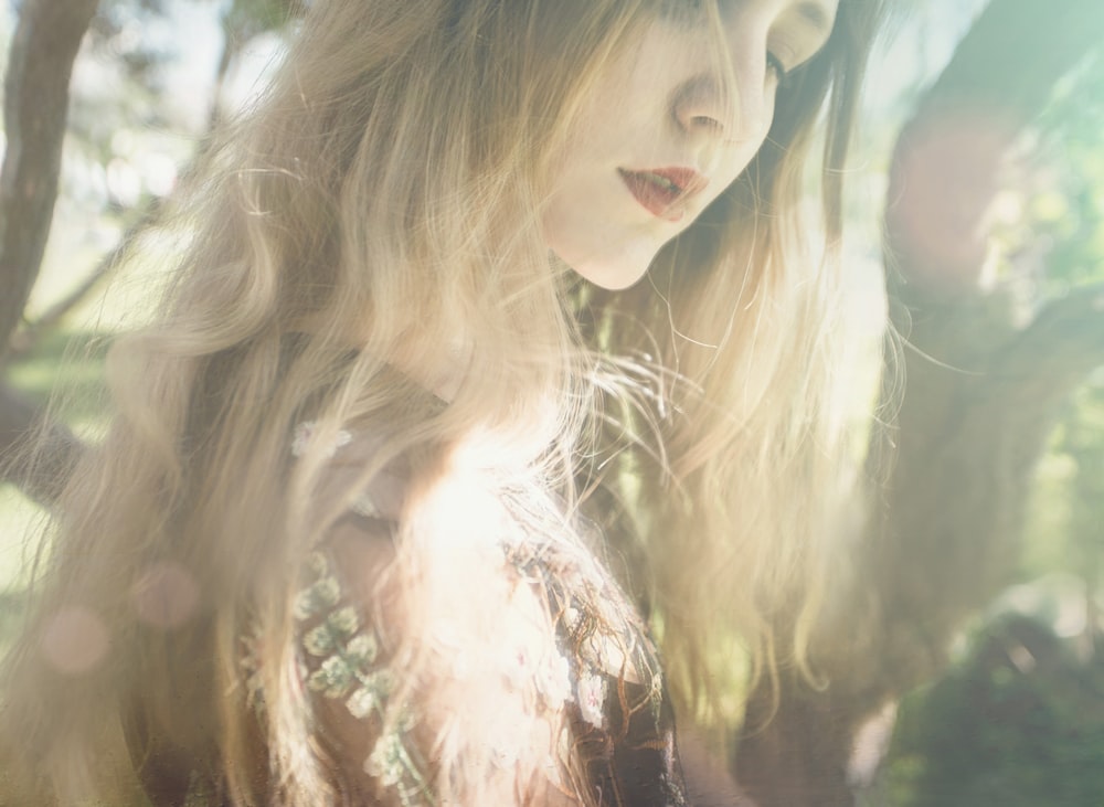 a woman with long hair standing under a tree