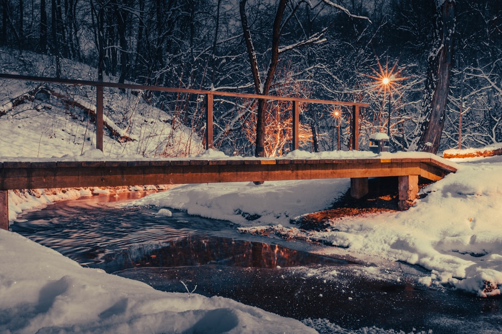 a wooden bridge over a small stream in the snow