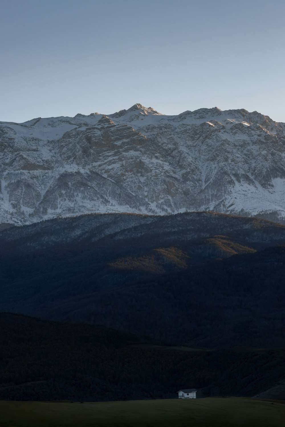 a snowy mountain range with a house in the foreground