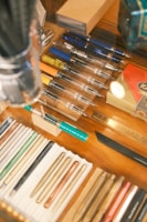 a wooden table topped with lots of books and pencils