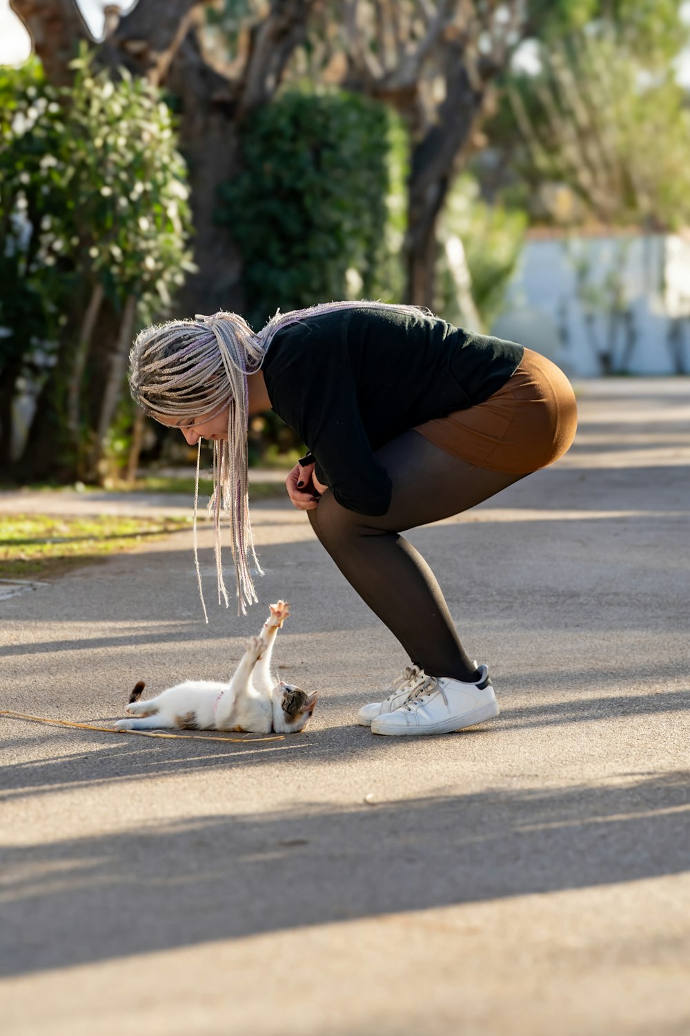a woman bending over to pet a cat